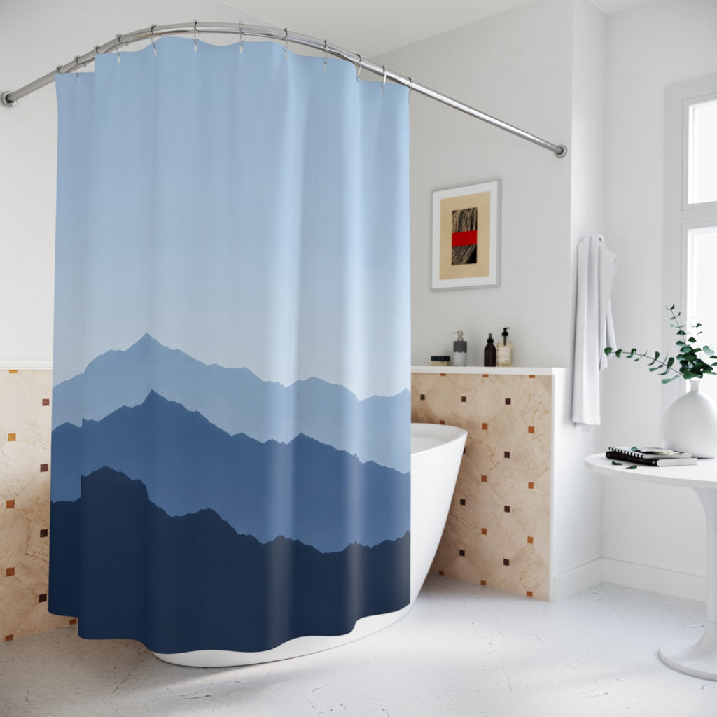 Layered pale blue, slate and indigo mountain ridges shower curtain beside a freestanding tub