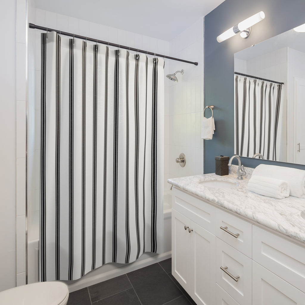 Fine black ticking stripe trios on white shower curtain beside a white vanity