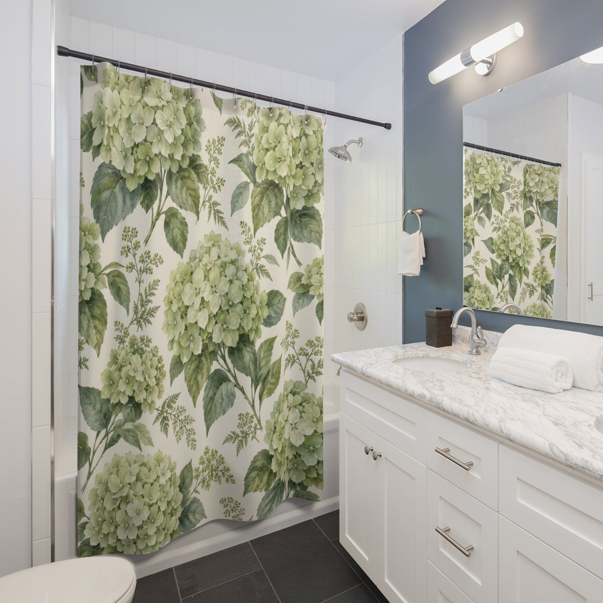 Sage-green hydrangea clusters and leaves on warm cream shower curtain beside a white vanity