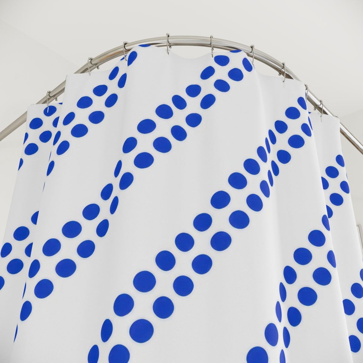Paired diagonal cobalt dot stripes on white shower curtain with close-up print, hooks, and folds