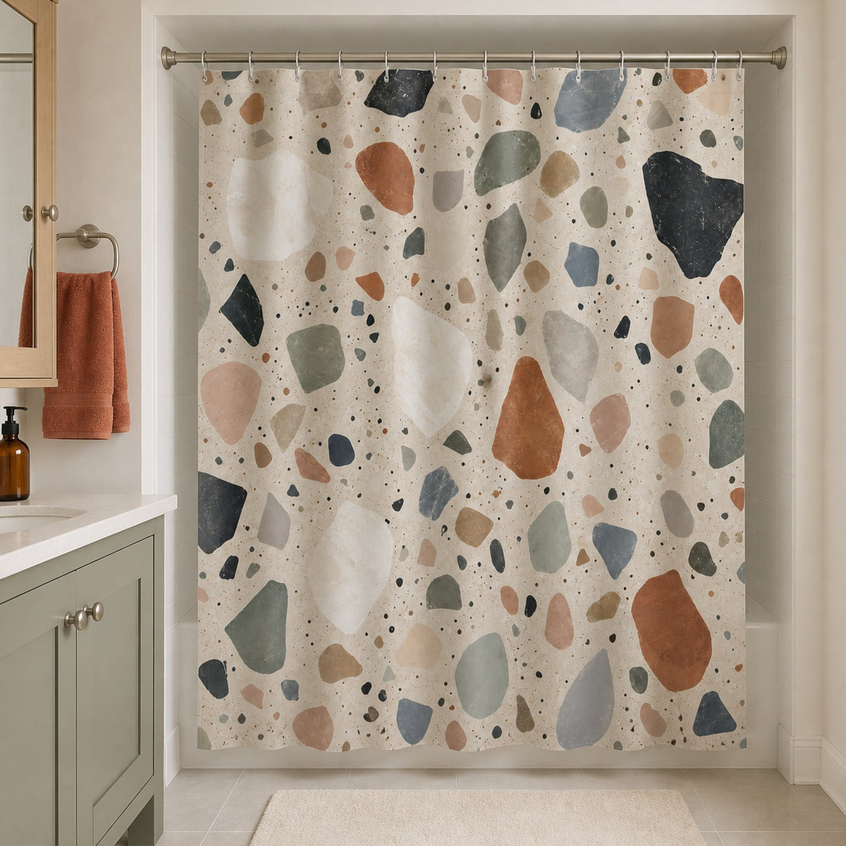 Multicolor stone chip shower curtain in a warm white hall bathroom with sage vanity and terracotta towel