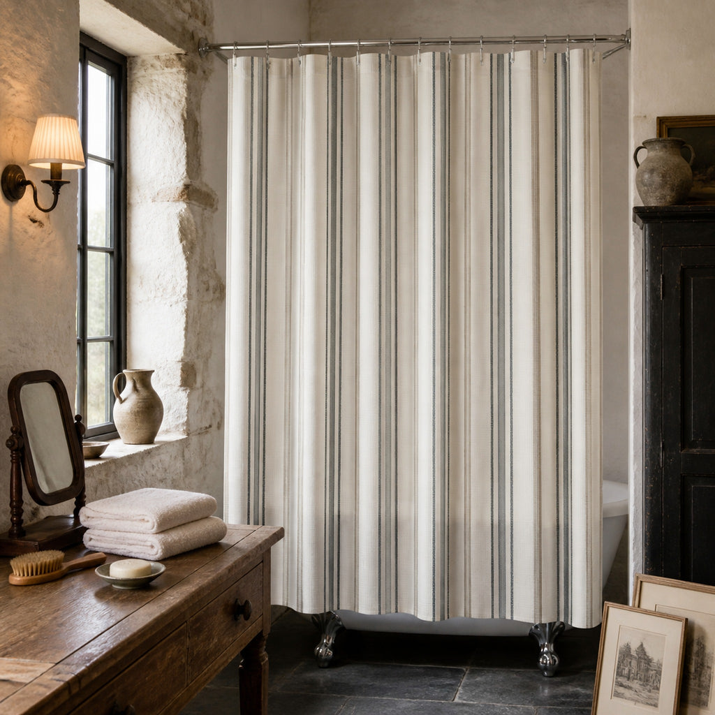 Charcoal and ivory ticking stripe shower curtain in a Normandy stone bathroom with antique oak and black furniture