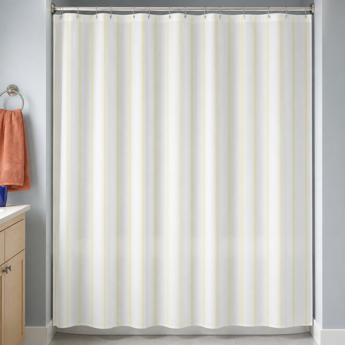 Pale yellow pinstripe shower curtain in a blue-gray bathroom with maple vanity and terracotta towel